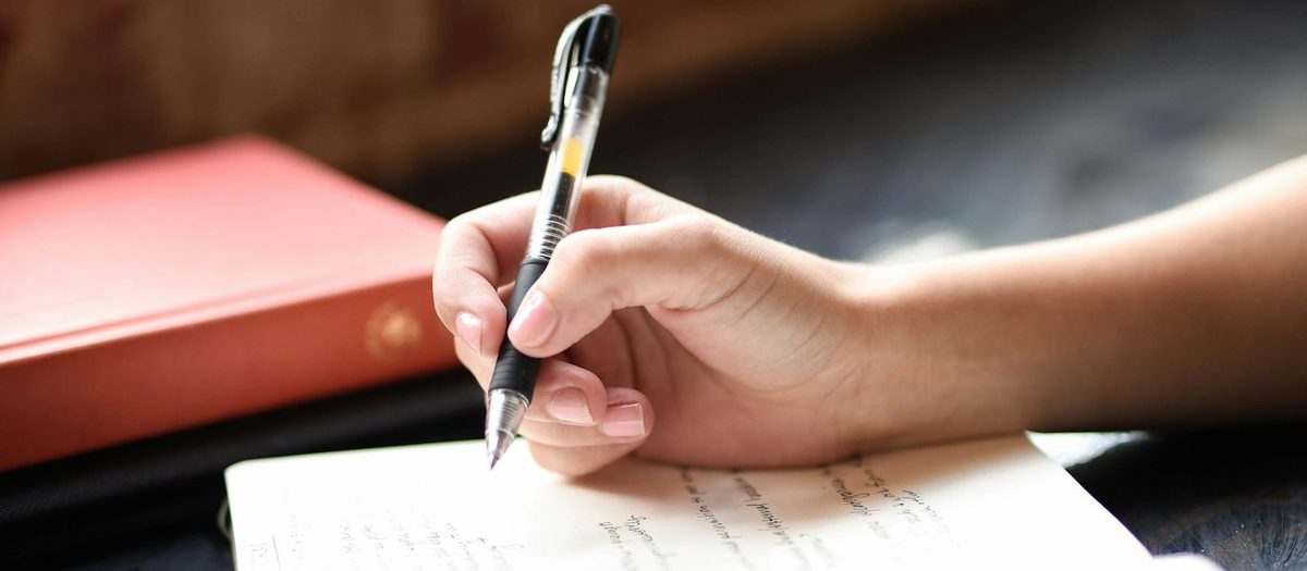 A student writing an early draft of an essay by hand